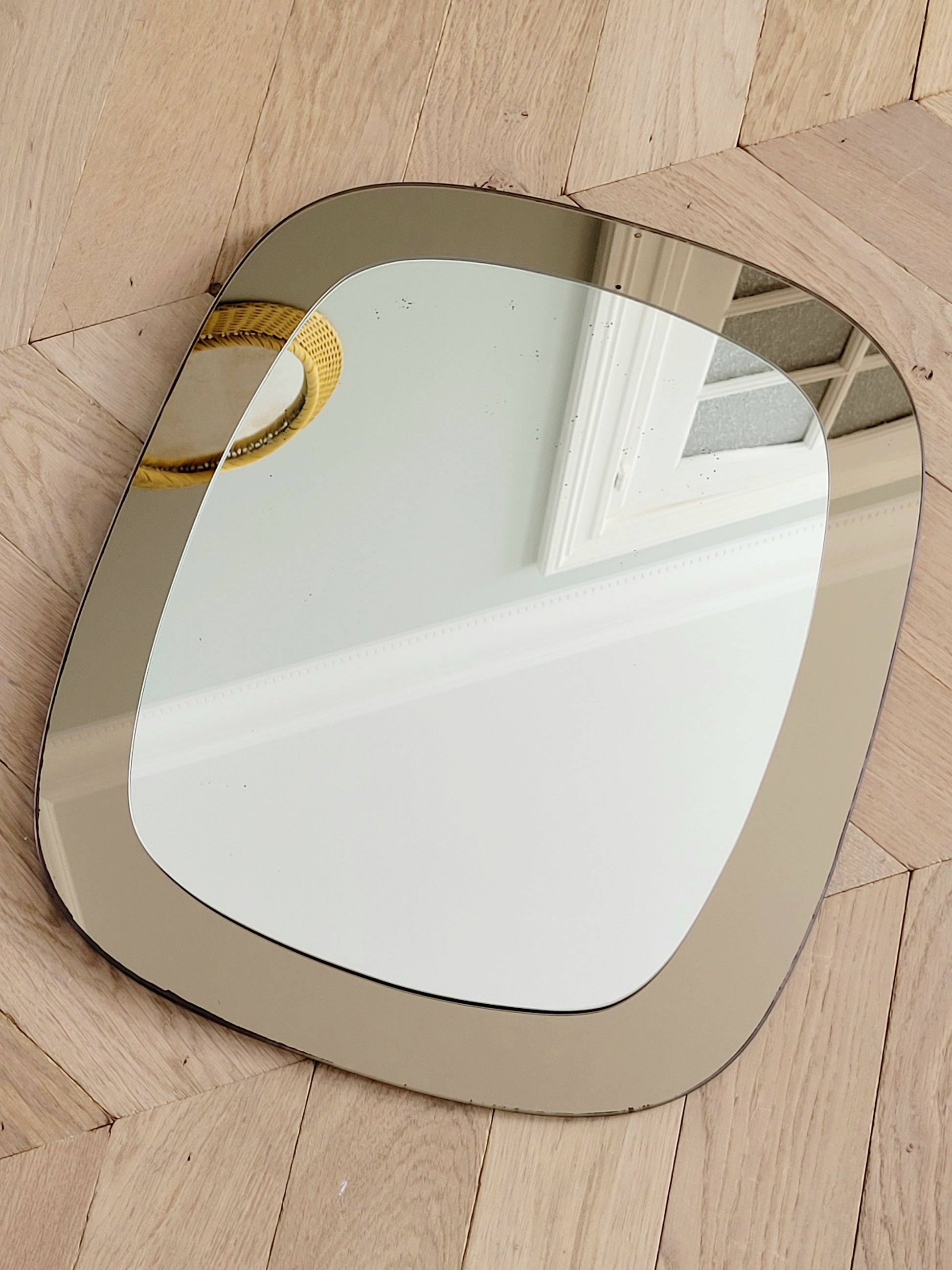 full view of a vintage two-tone Italian wall mirror with smoked glass