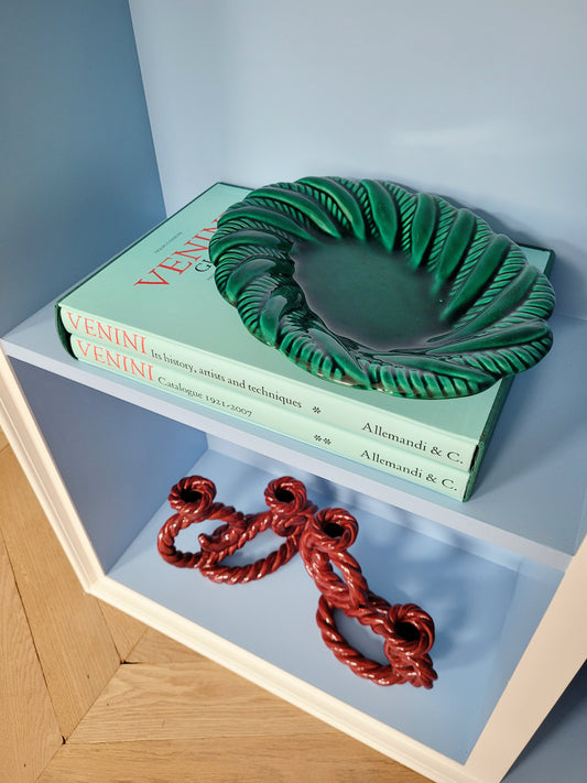 top view of a vintage green ceramic plate on a blue shelf