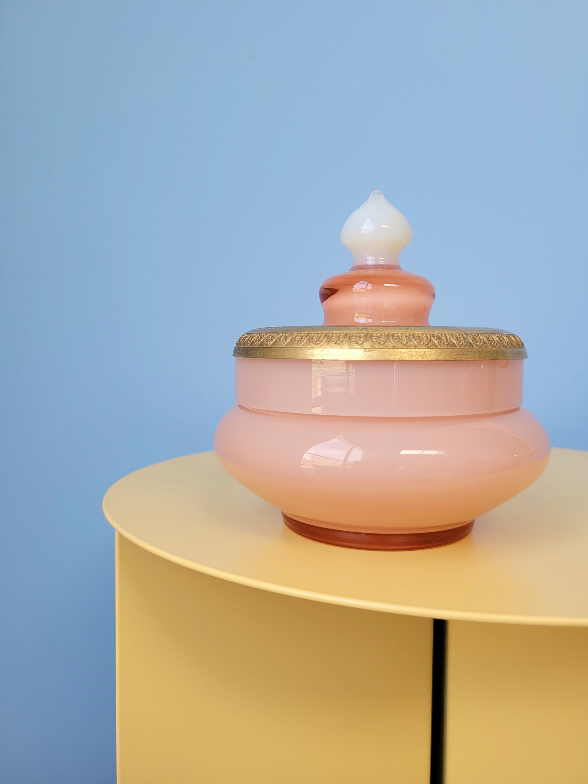 front view of a vintage opal pink glass bonbonniere on a yellow side table