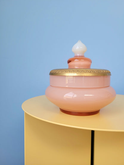 front view of a vintage opal pink glass bonbonniere on a yellow side table