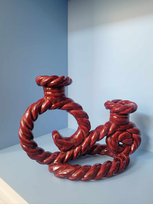 front view of a vintage red twisted ceramic candle holder in a blue cabinet
