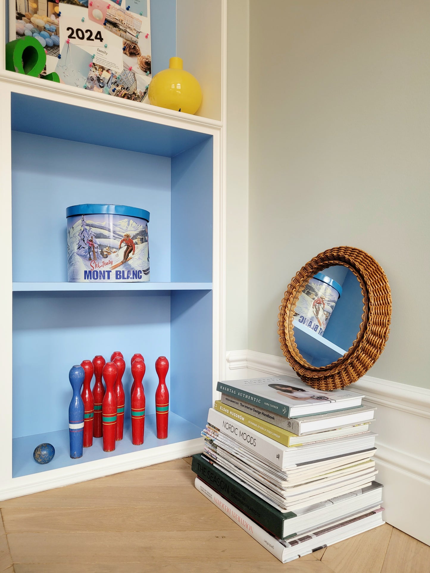 side view of a vintage woven round wall mirror stacked on top of a pile of books
