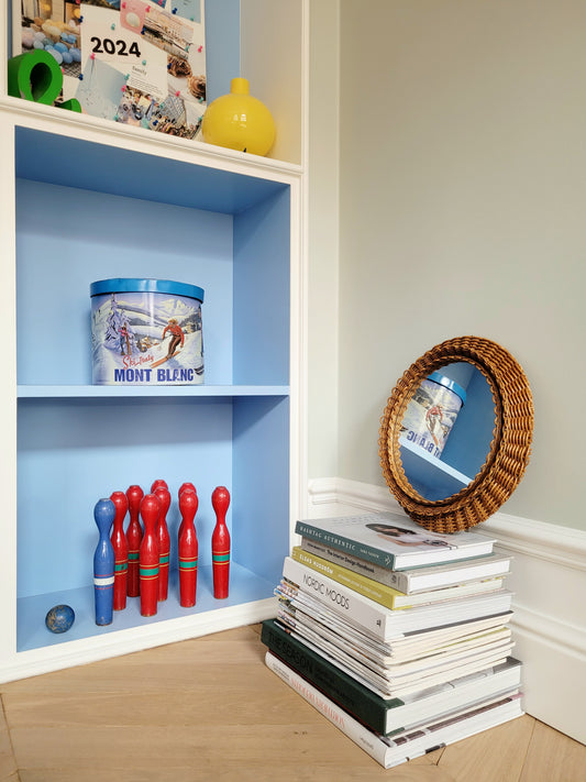 side view of a vintage woven round wall mirror stacked on top of a pile of books
