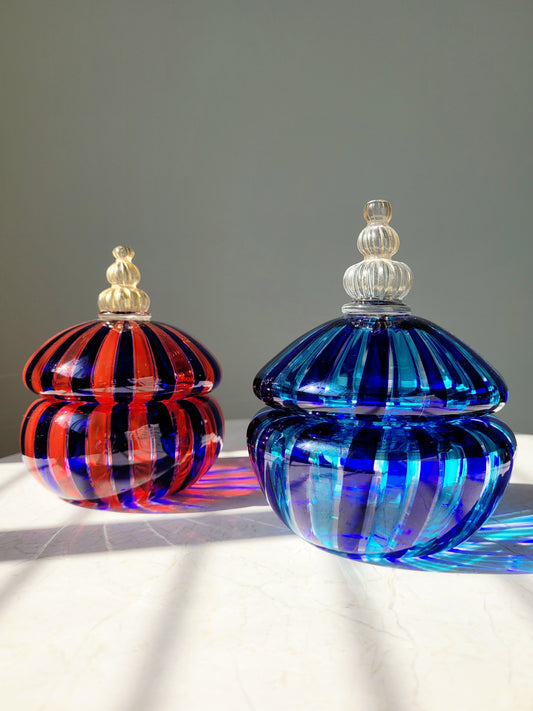 full view of two handcrafted vintage striped Murano bonbonnieres on a marble side table