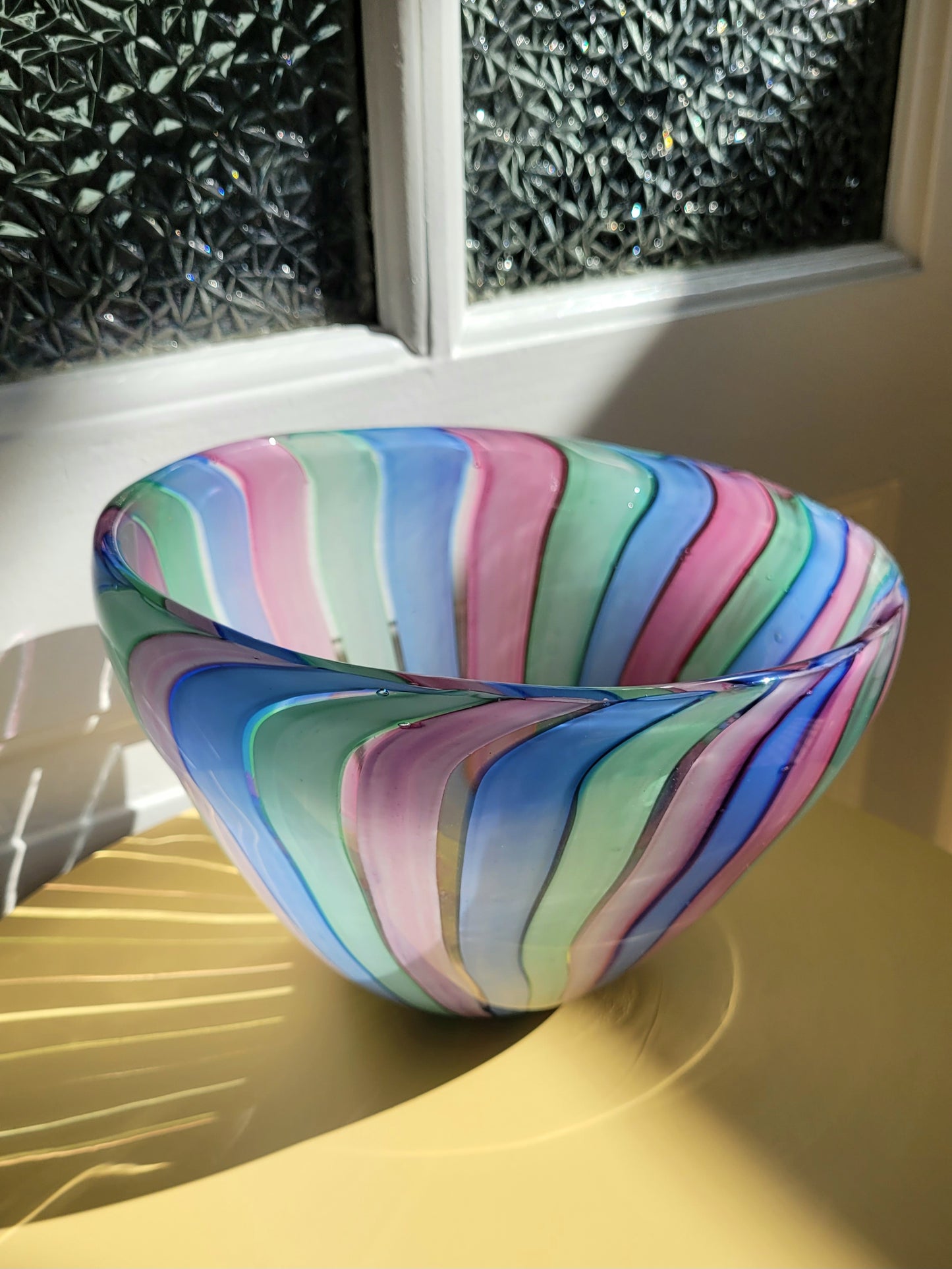 detail of a vintage candy stripe Murano bowl on a yellow side table