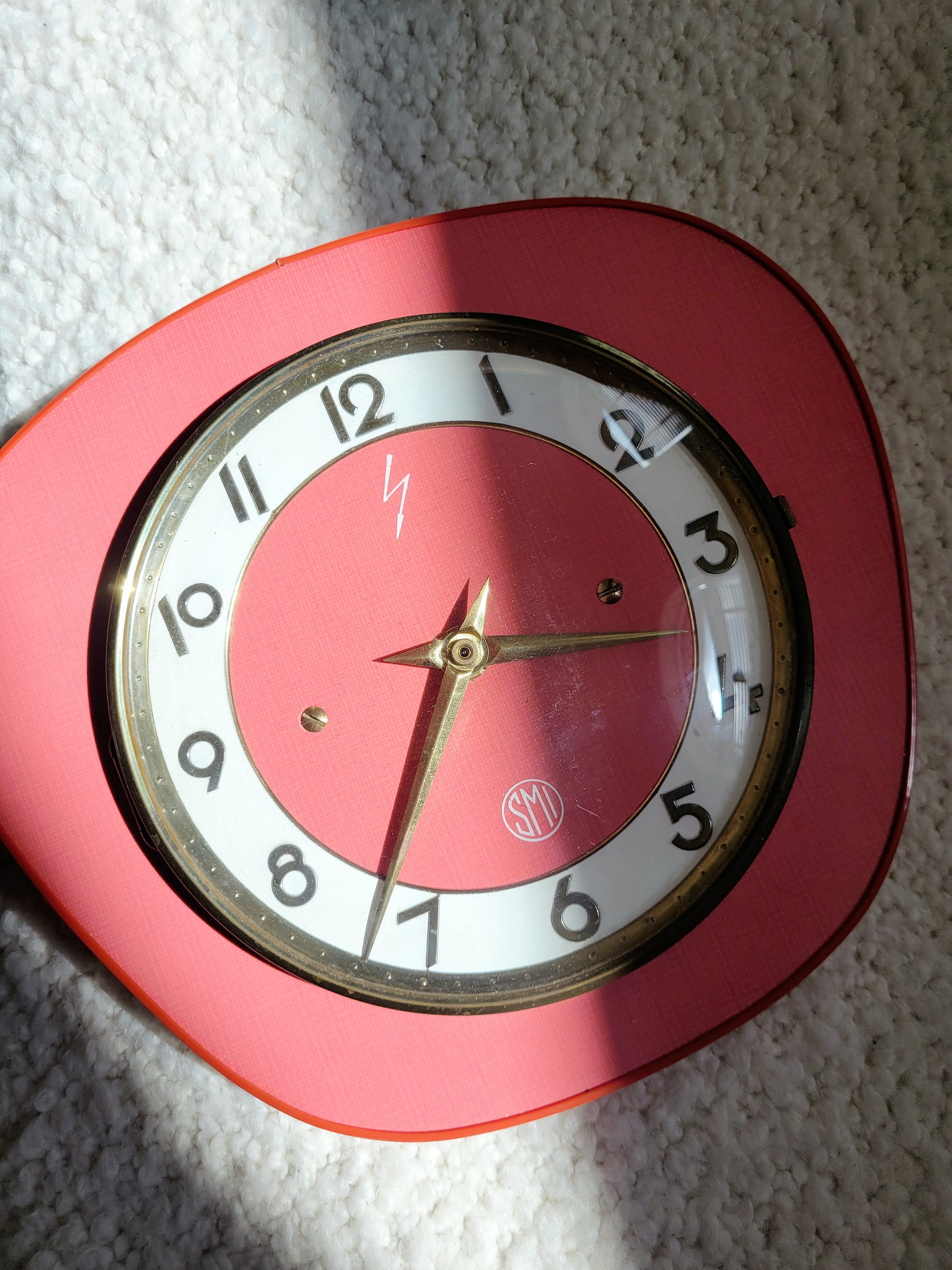 top view of a red wall clock of the French brand SMI in formica with a brass ring and curved glass