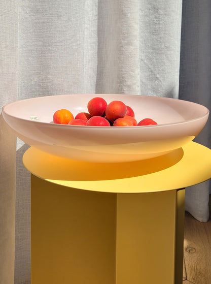 front view of a large vintage opal pink Murano bowl on a yellow side table