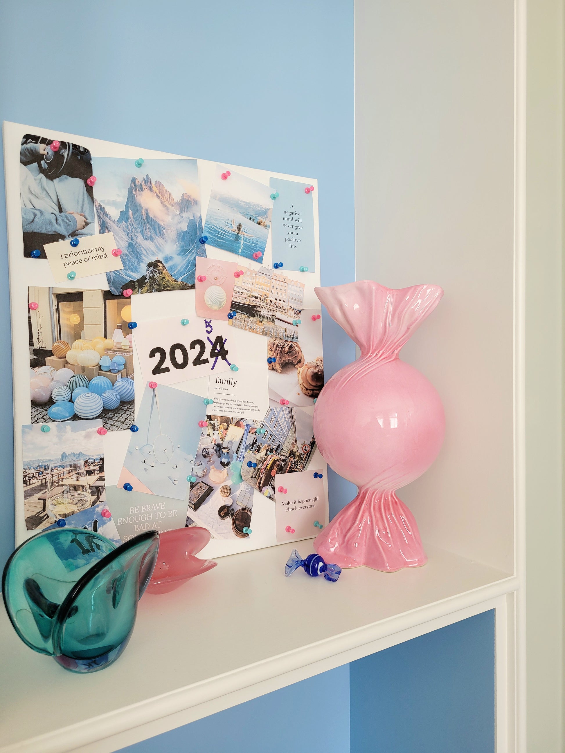full view of a pink ceramic candy bonbon vase with a vision board next to it and a small Murano candy and Murano clam bowls in the front