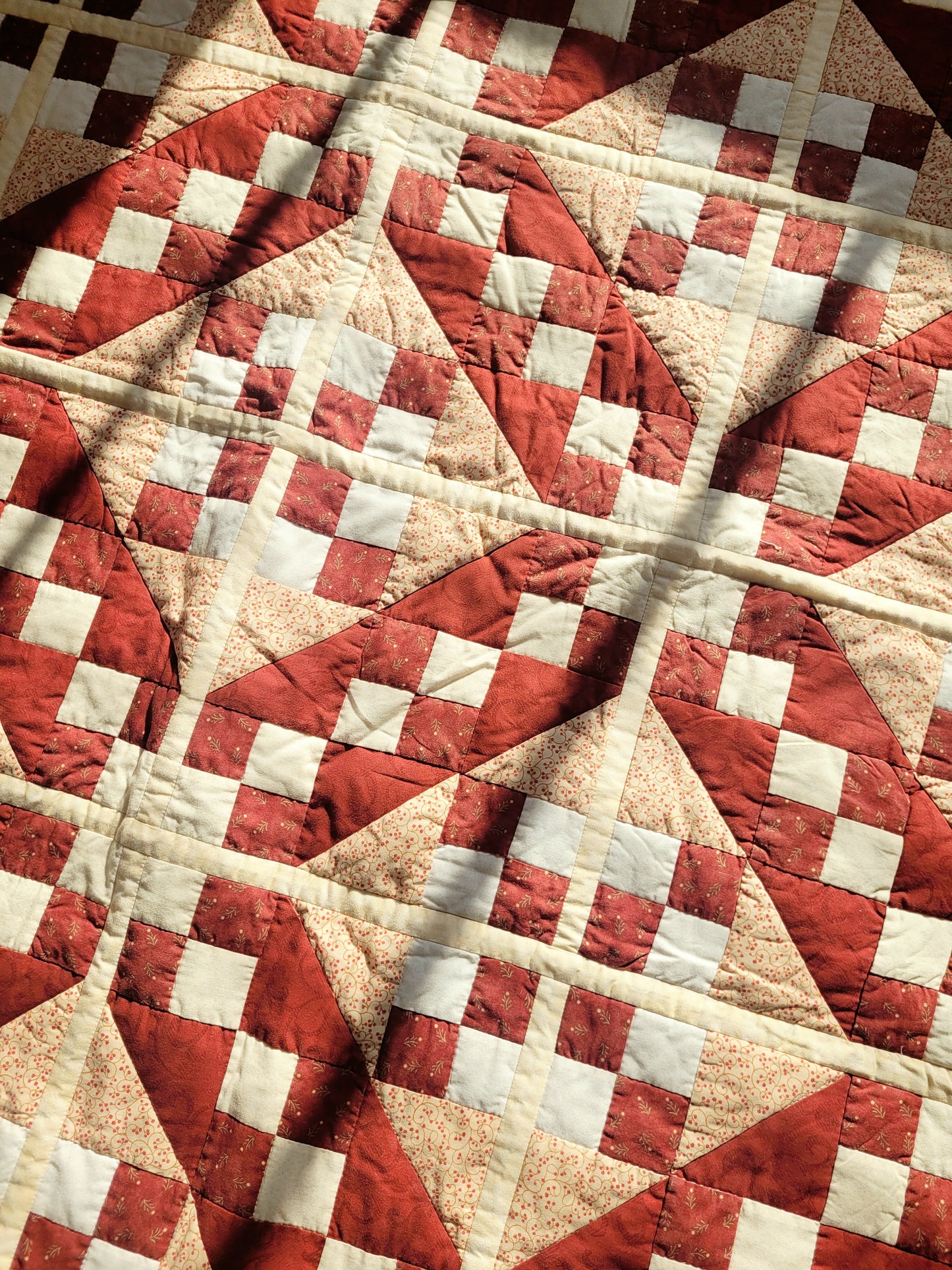 detail of a handmade red and beige patchwork quilt
