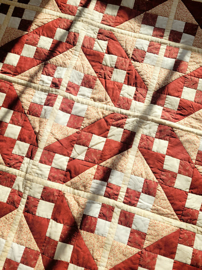detail of a handmade red and beige patchwork quilt