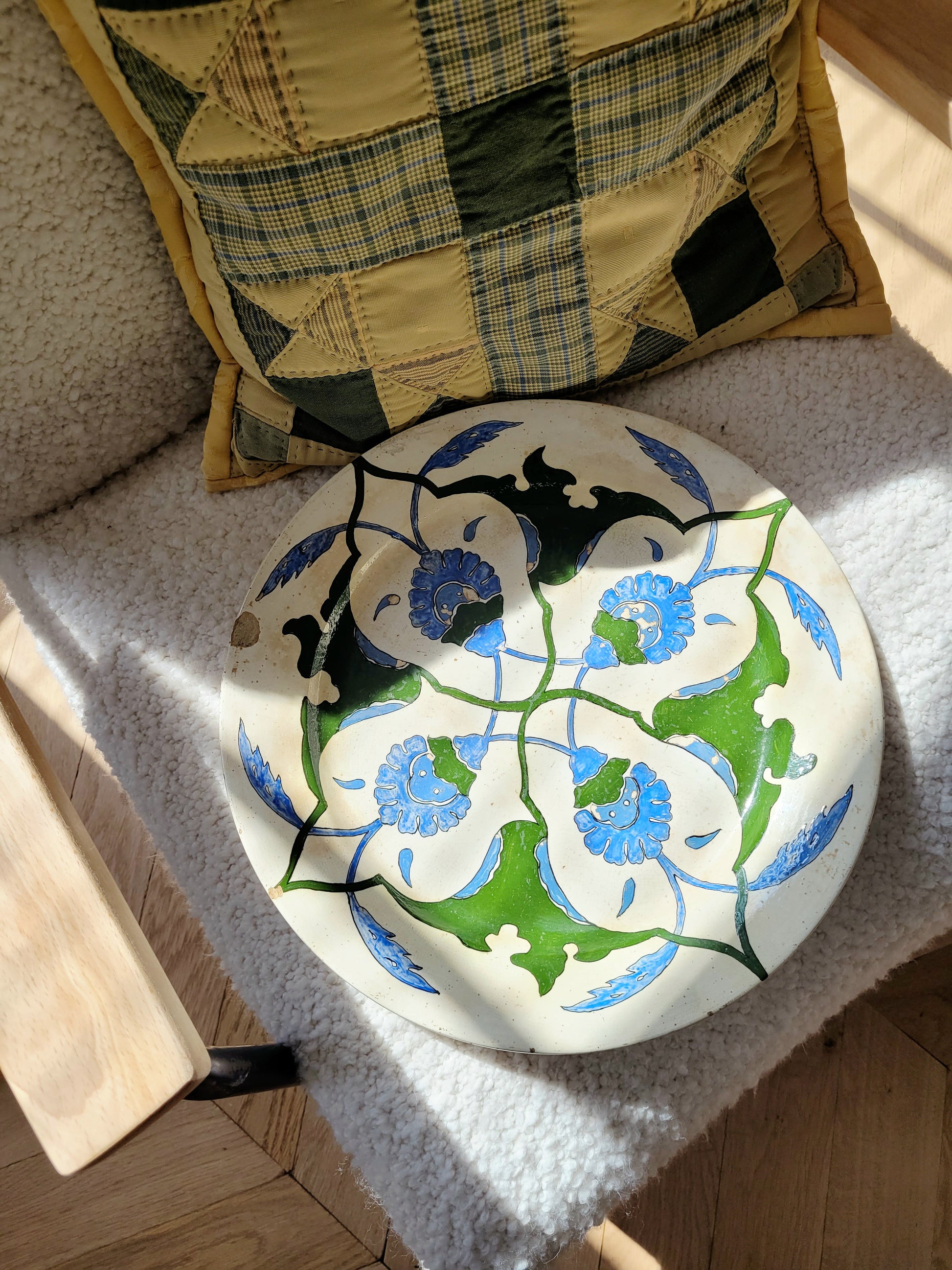 top view of a vintage Italian (wall) plate with blue and green floral motif, made by Fontebasso Treviso, Italy on a white chair in the sunlight