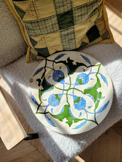 top view of a vintage Italian (wall) plate with blue and green floral motif, made by Fontebasso Treviso, Italy on a white chair in the sunlight