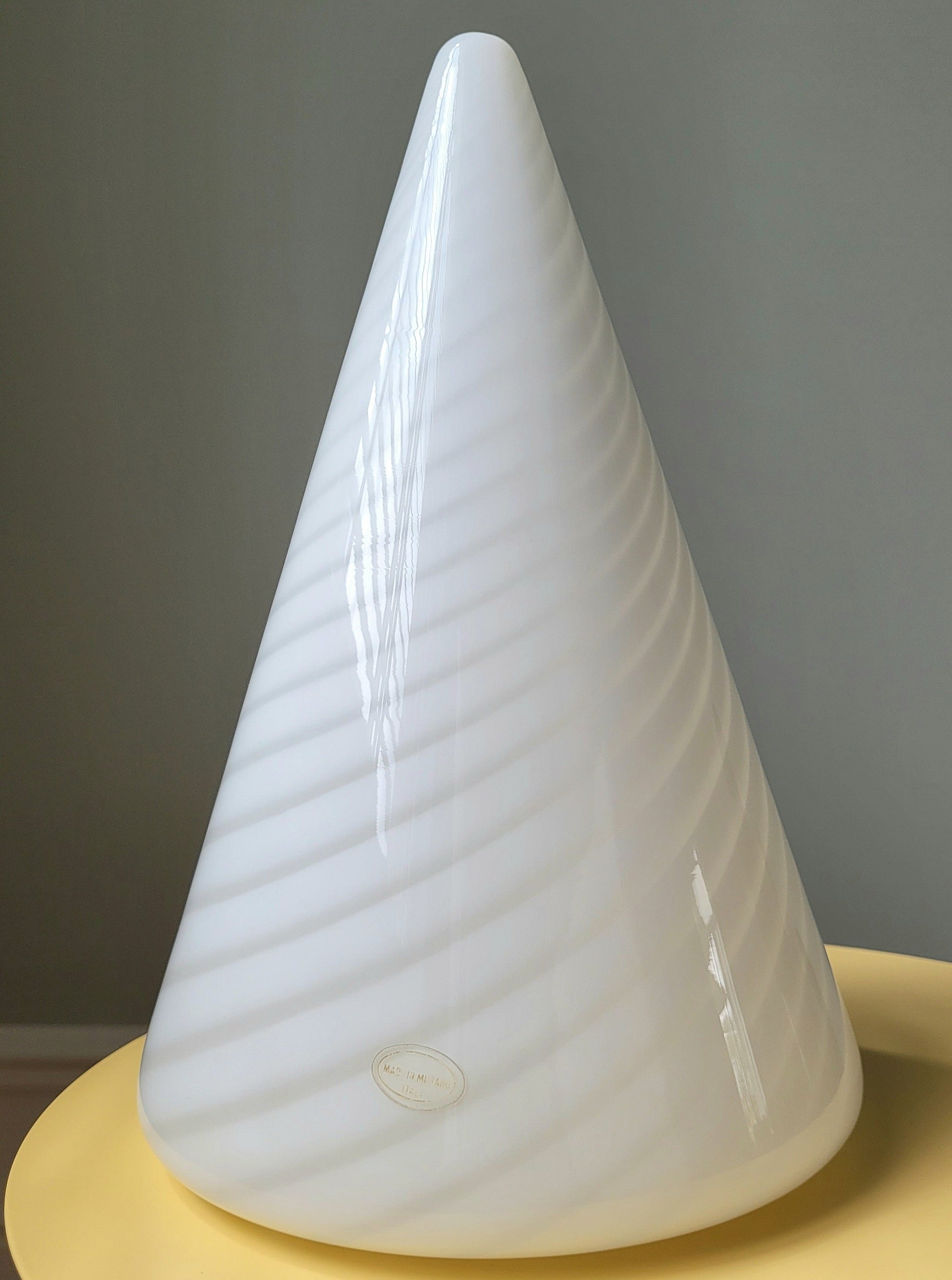 front view of a vintage Murano cone lamp with white and translucent swirl on a yellow side table