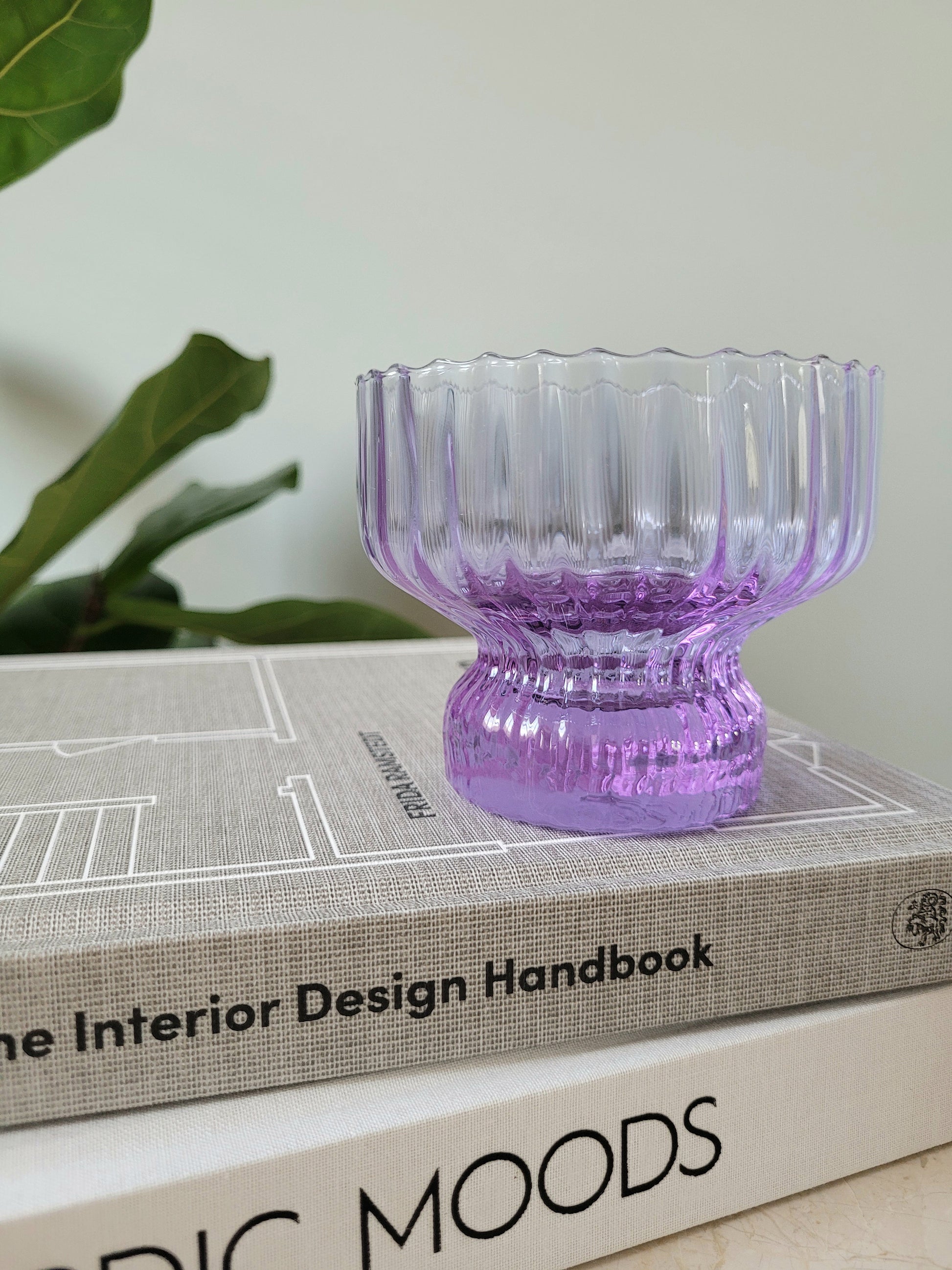 detail of a purple Italian glass and cup on a stack of interior books