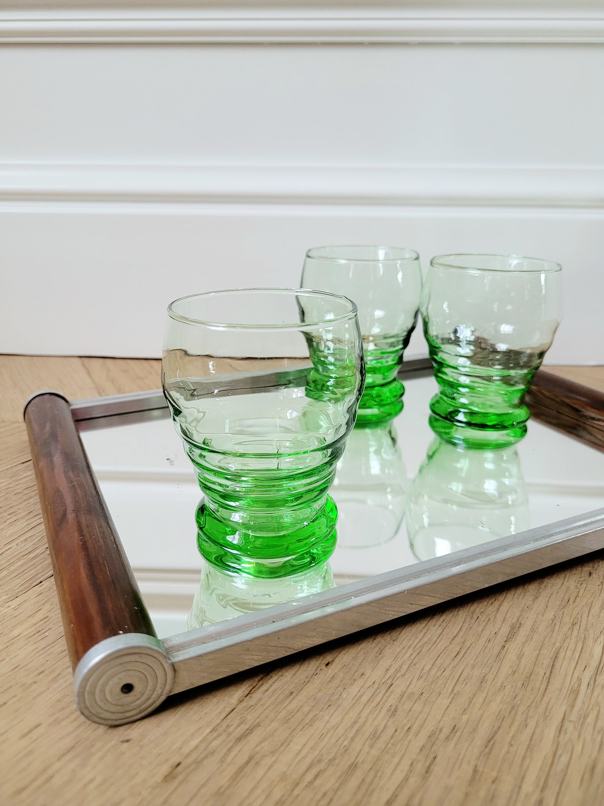 front view of bright green art deco drinking glasses on a mirror tray