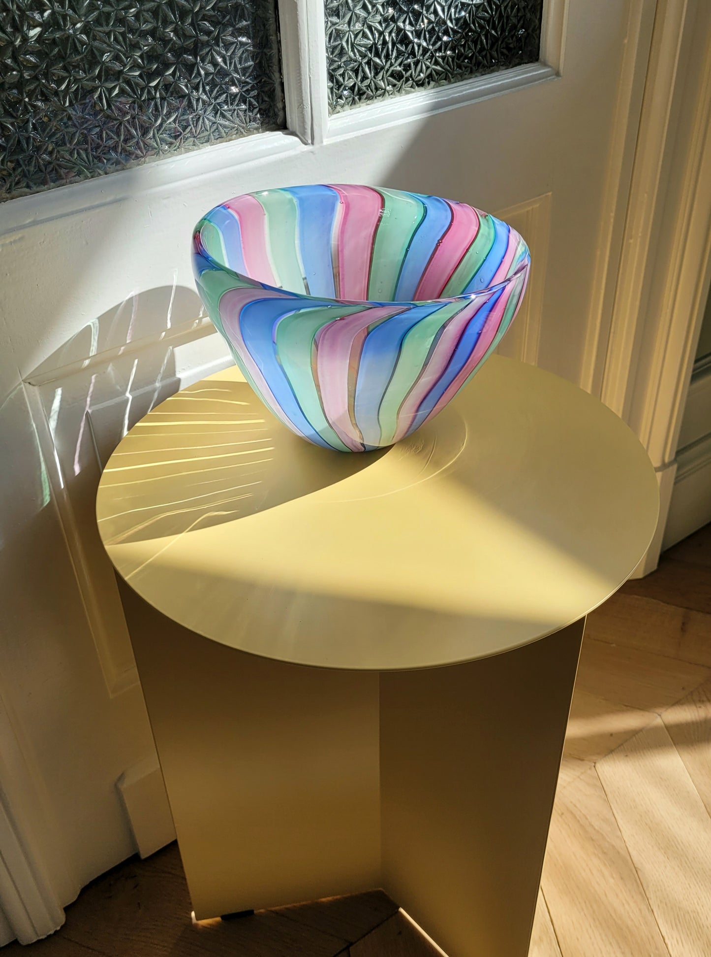 overview of a vintage candy stripe Murano bowl on a yellow side table