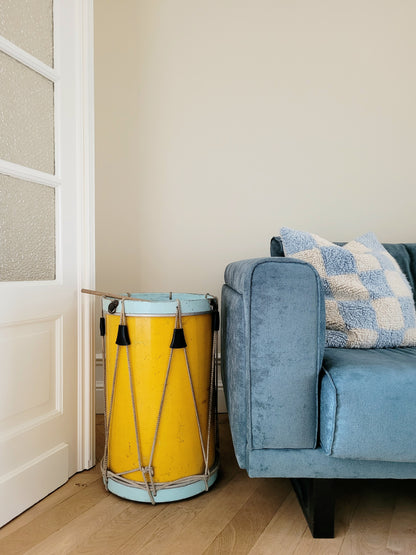 front view of a colourful rope tension drum in vibrant colours in use as a side table next to a sofa
