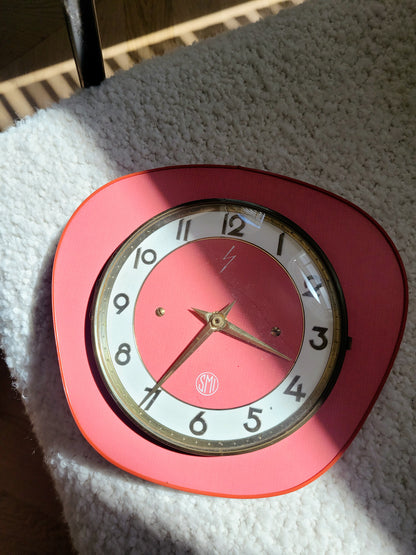 top view of a red wall clock of the French brand SMI in formica with a brass ring and curved glass