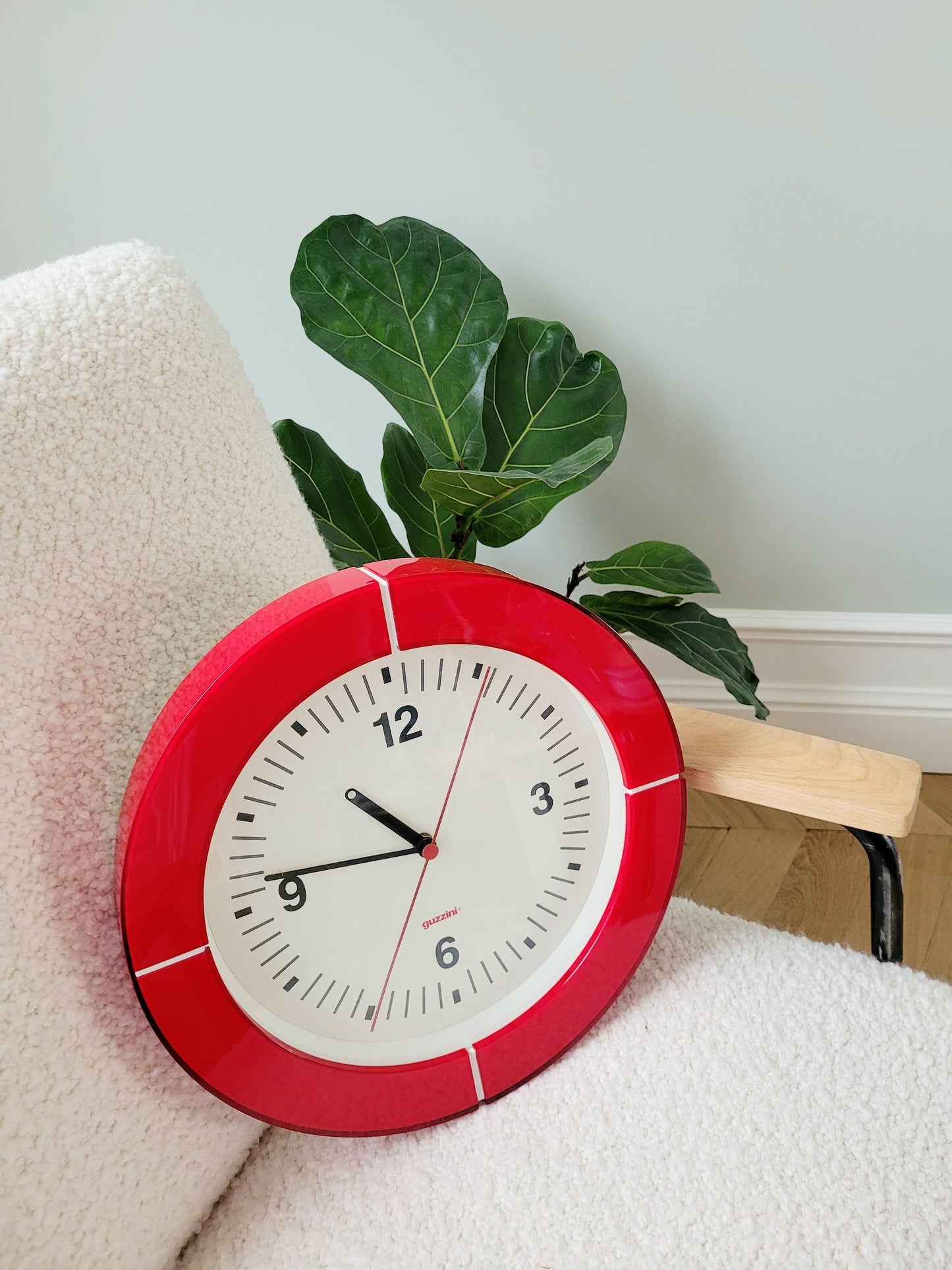 side view of a Guzzini acrylic red wall clock on an armchair