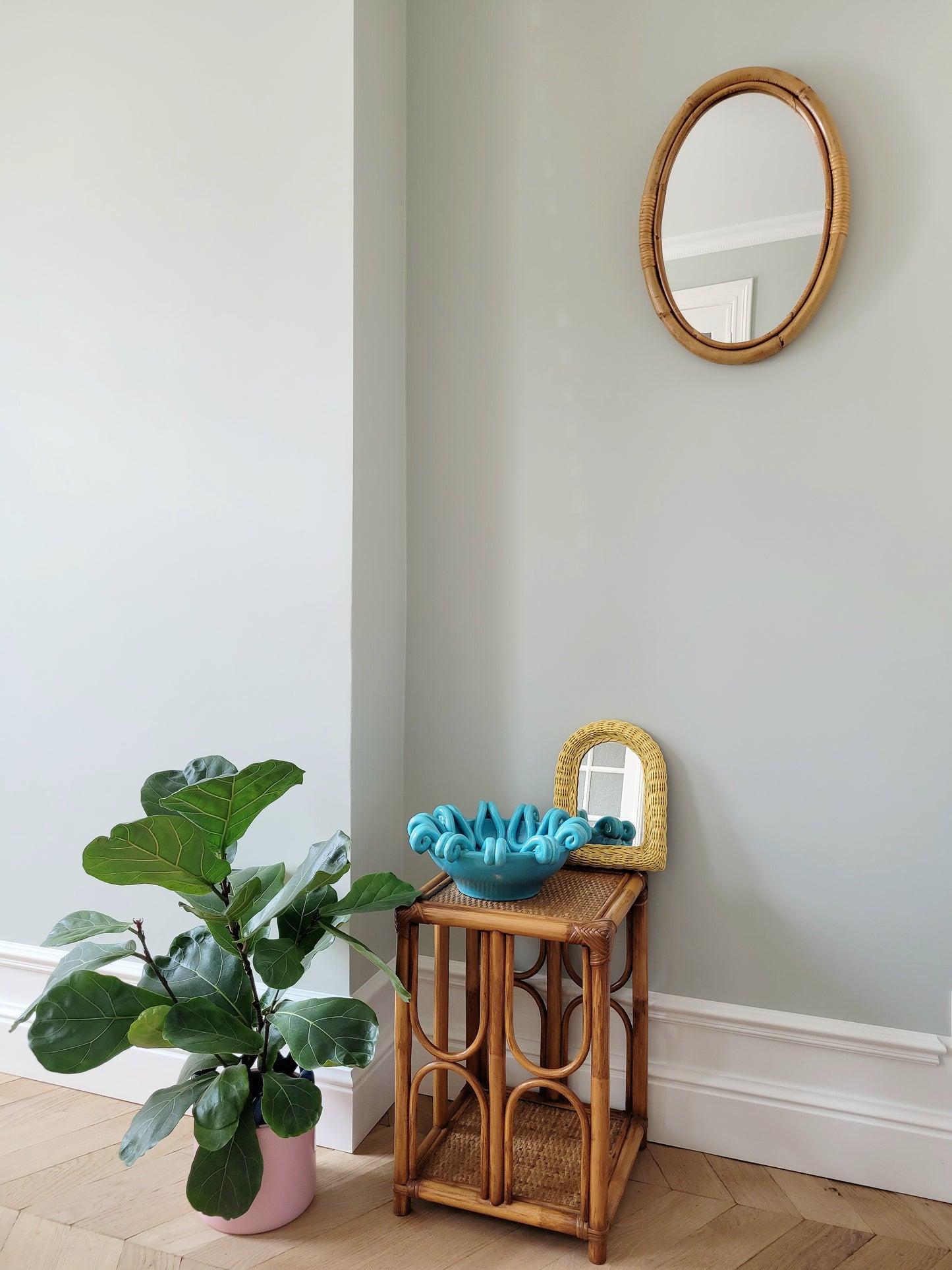 full view of an oval wall mirror in natural bamboo with a side table