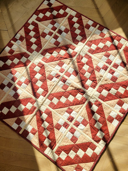 full view of a handmade red and beige patchwork quilt