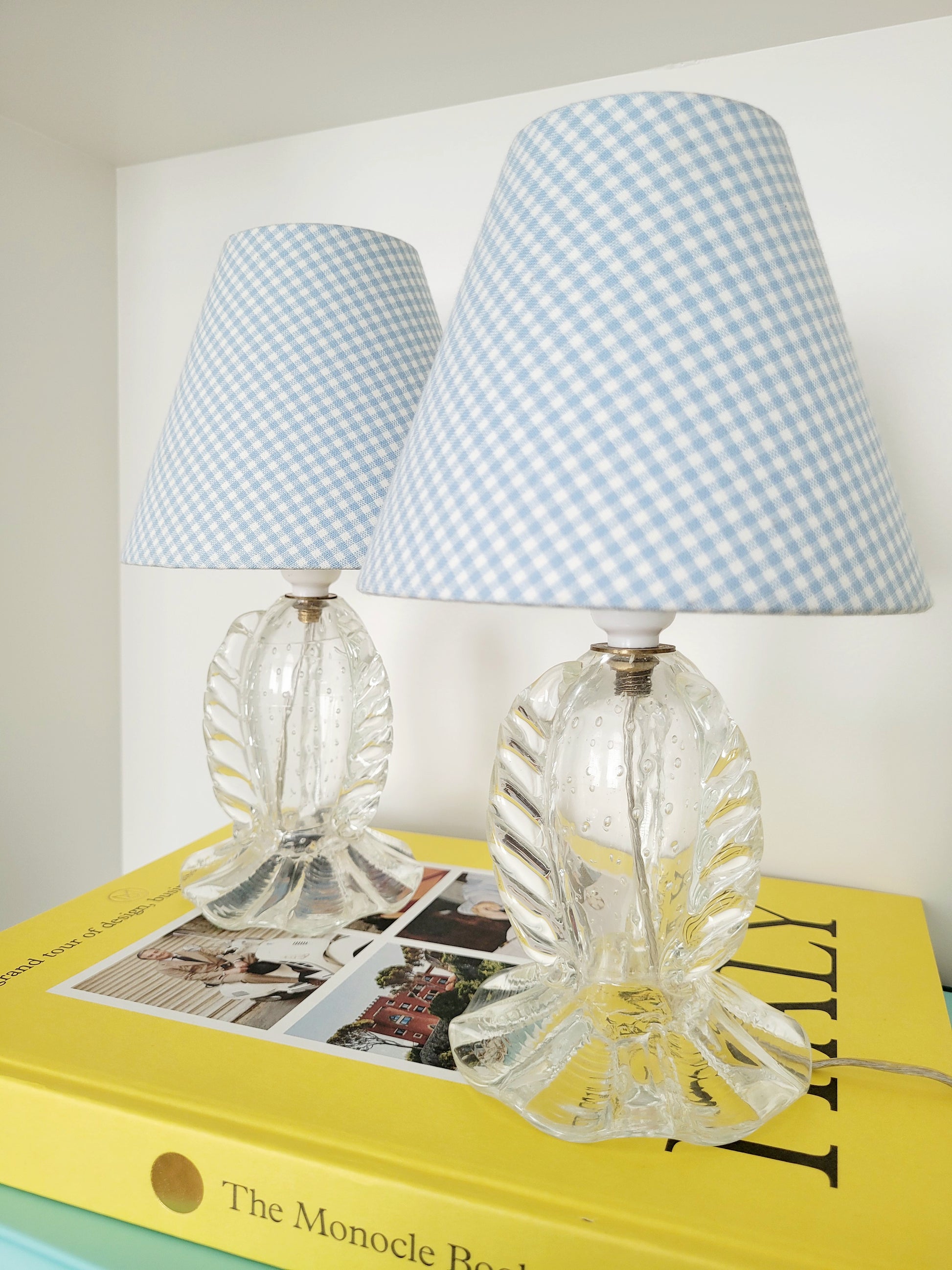 front view of a rare pair of vintage clear Murano table lamps with shades stacked on books 