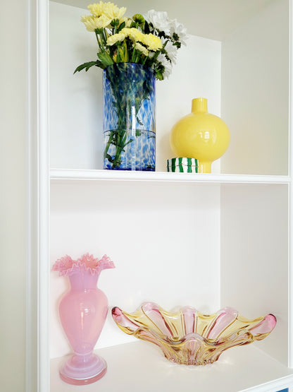 full view of a vibrant candy coloured glass serving or trinket bowl in yellow and pink on white shelves