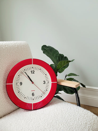 full view of a Guzzini acrylic red wall clock on an armchair