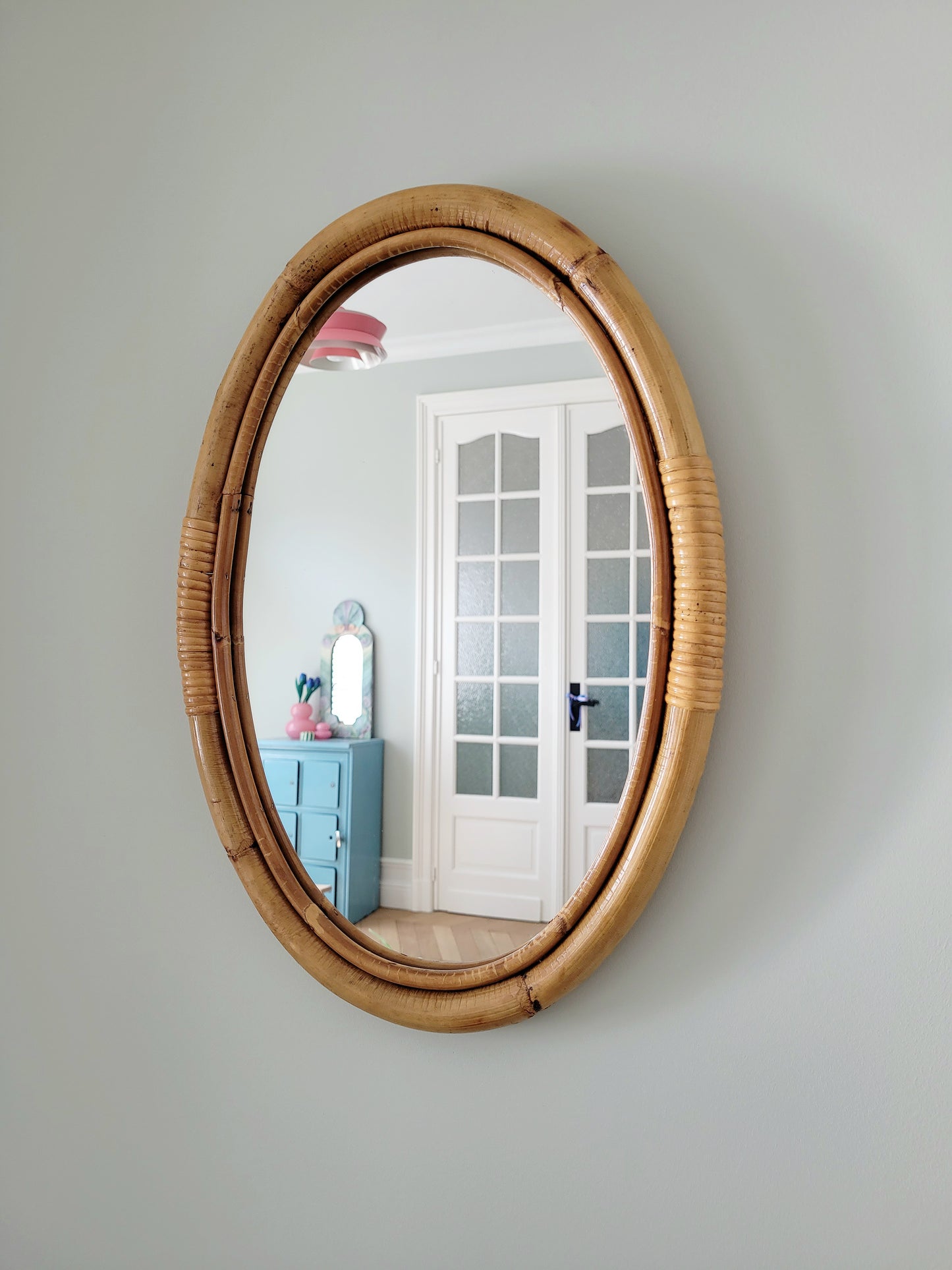 front view of an oval wall mirror in natural bamboo