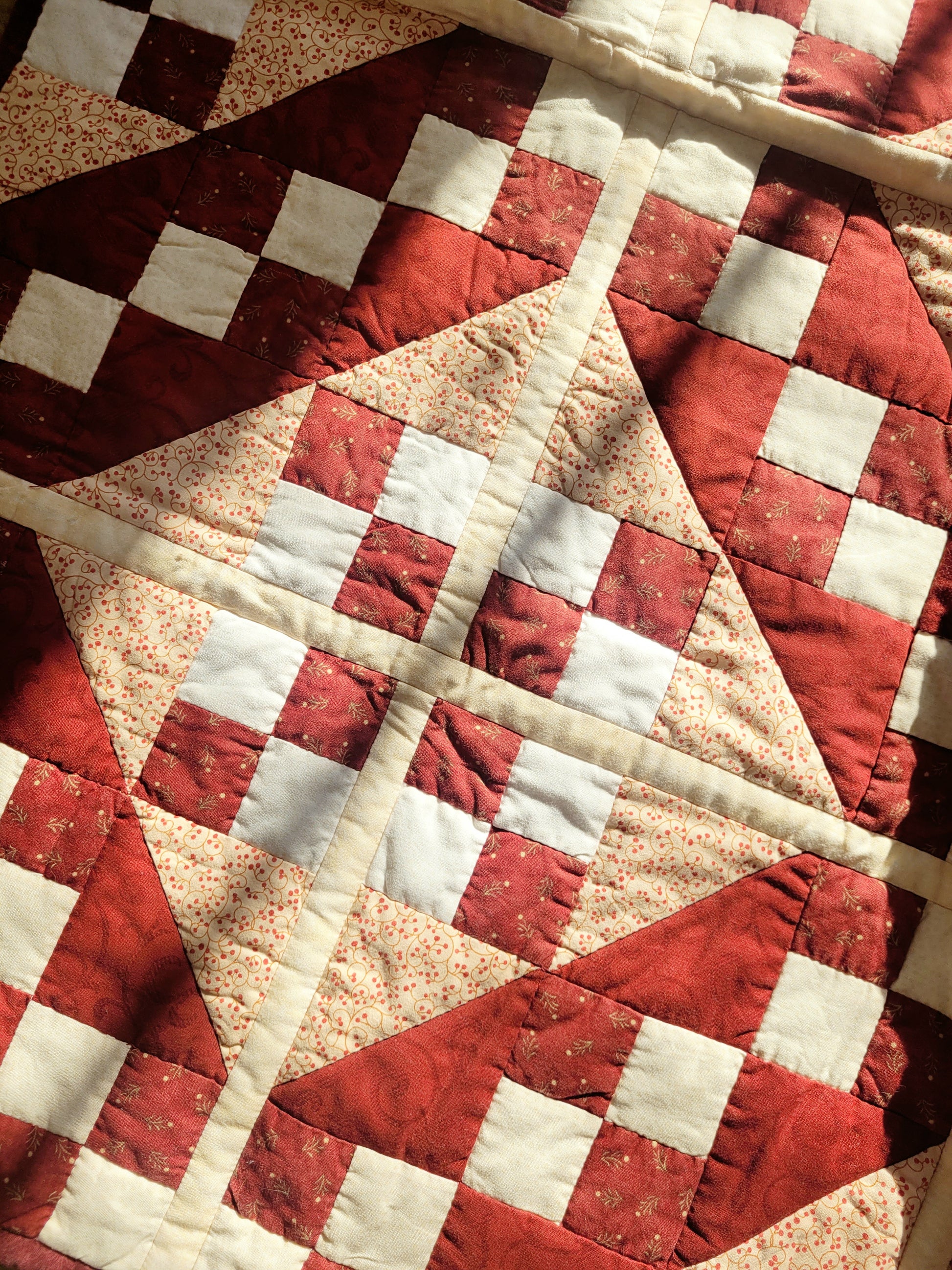detail of a handmade red and beige patchwork quilt