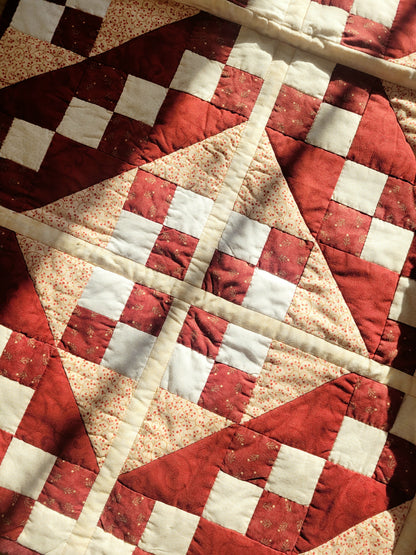 detail of a handmade red and beige patchwork quilt