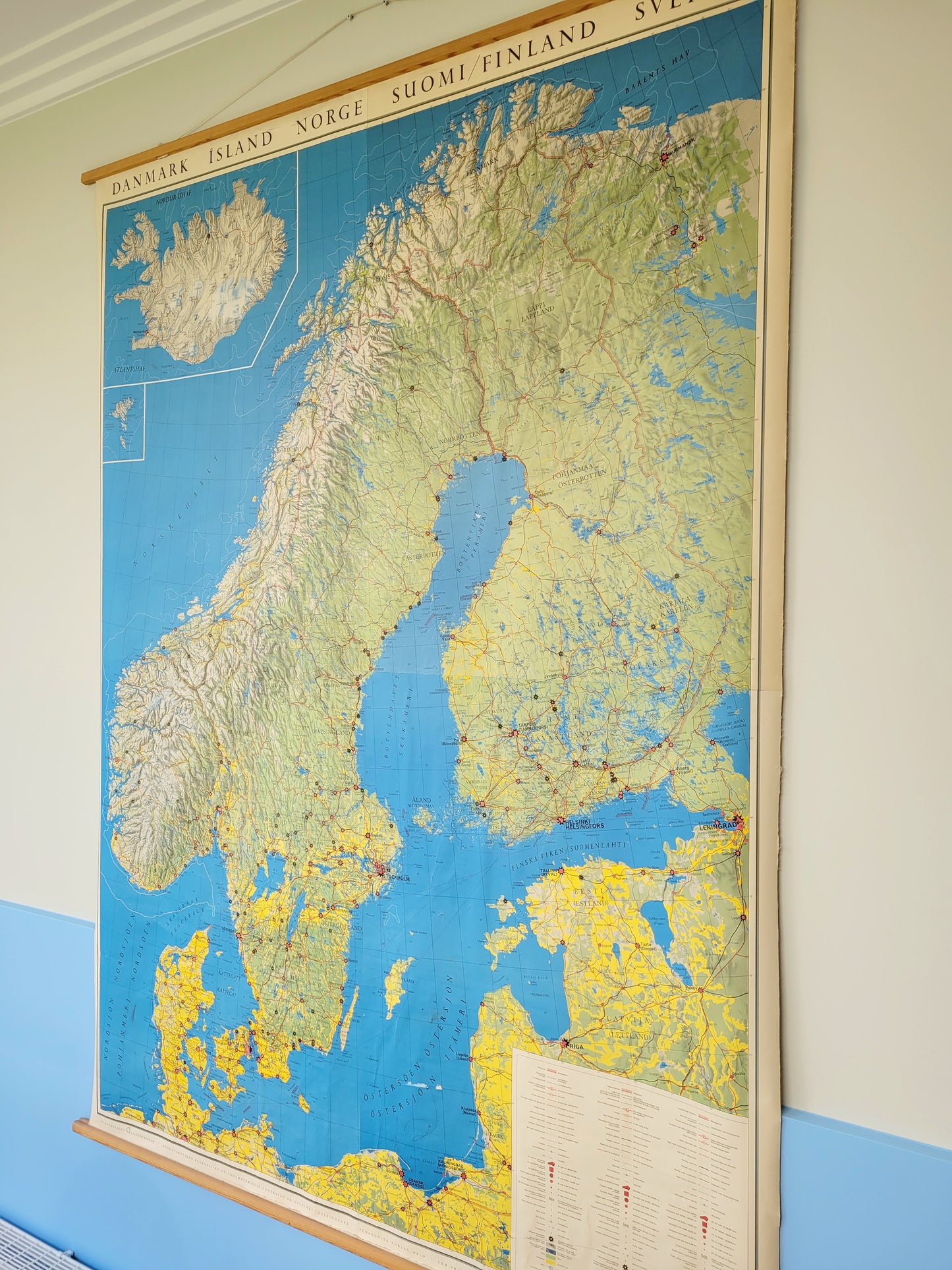 side view of a large historic school map of the Nordic countries hanging on a blue and yellow wall