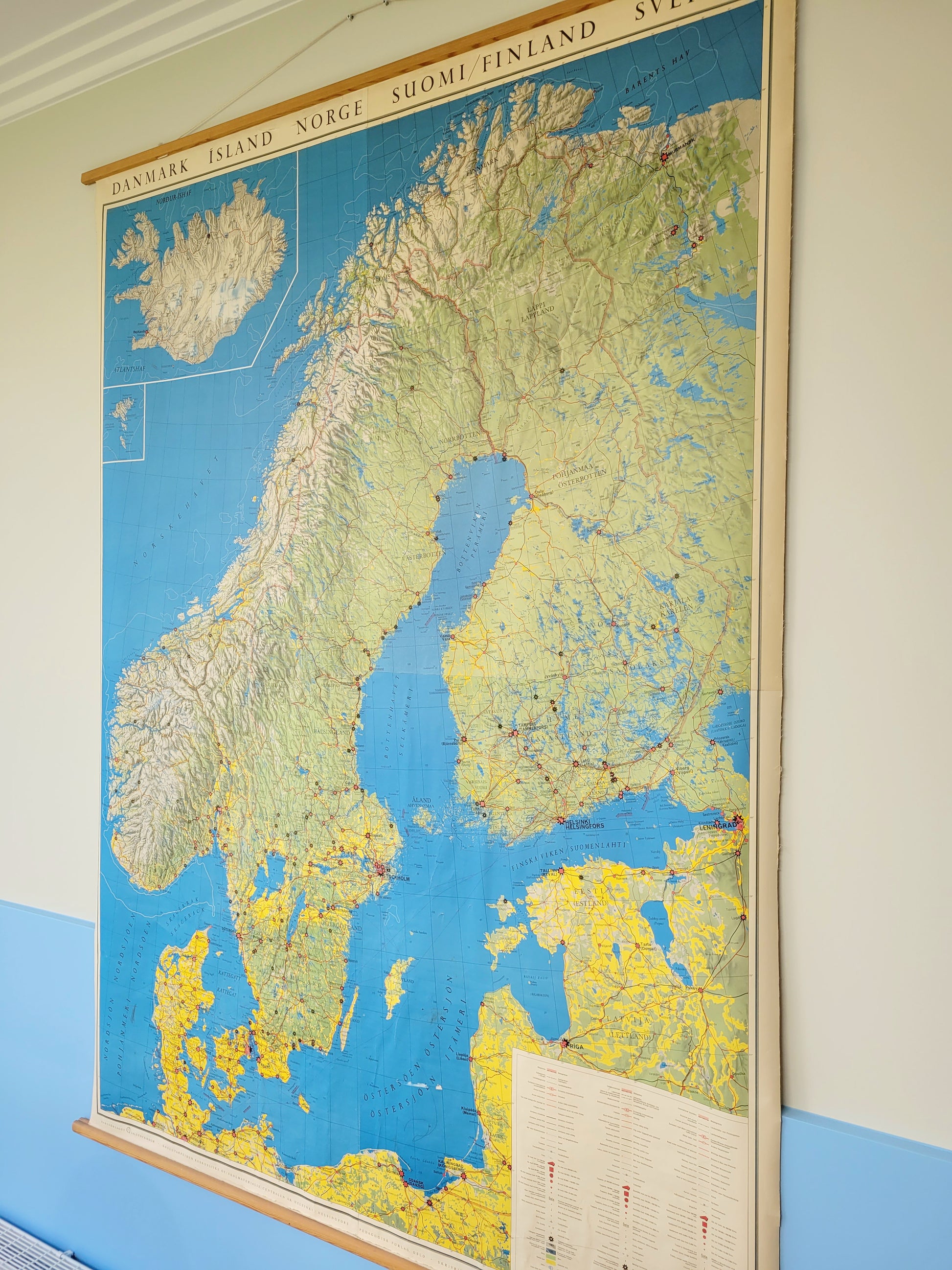 side view of a large historic school map of the Nordic countries hanging on a blue and yellow wall