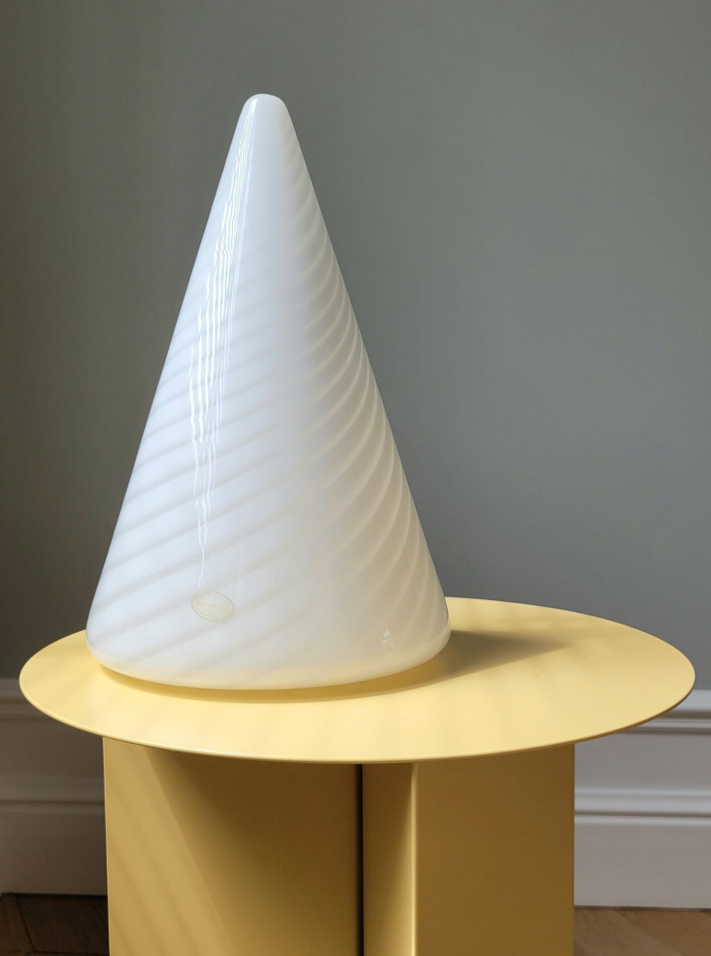 full view of a vintage Murano cone lamp with white and translucent swirl on a yellow side table