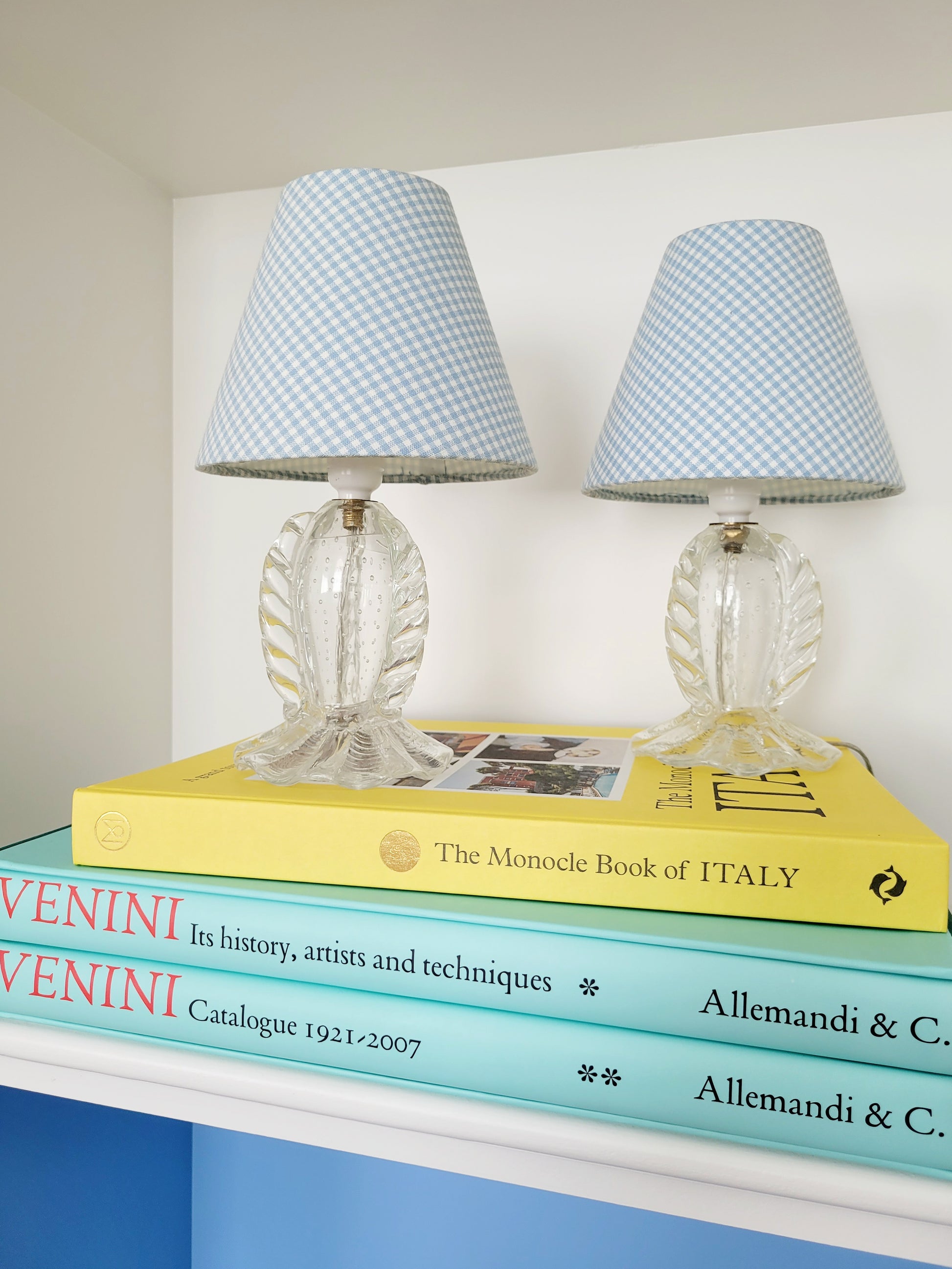 full view of a rare pair of vintage clear Murano table lamps with shades stacked on books 