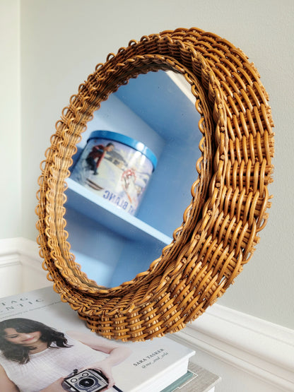 detail of a vintage woven round wall mirror stacked on top of a pile of books