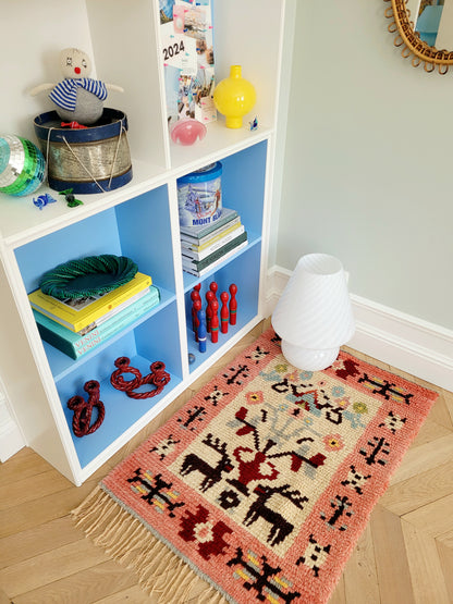 side view of a vintage colourful Scandinavian Rya rug made from wool with filled cabinets in background