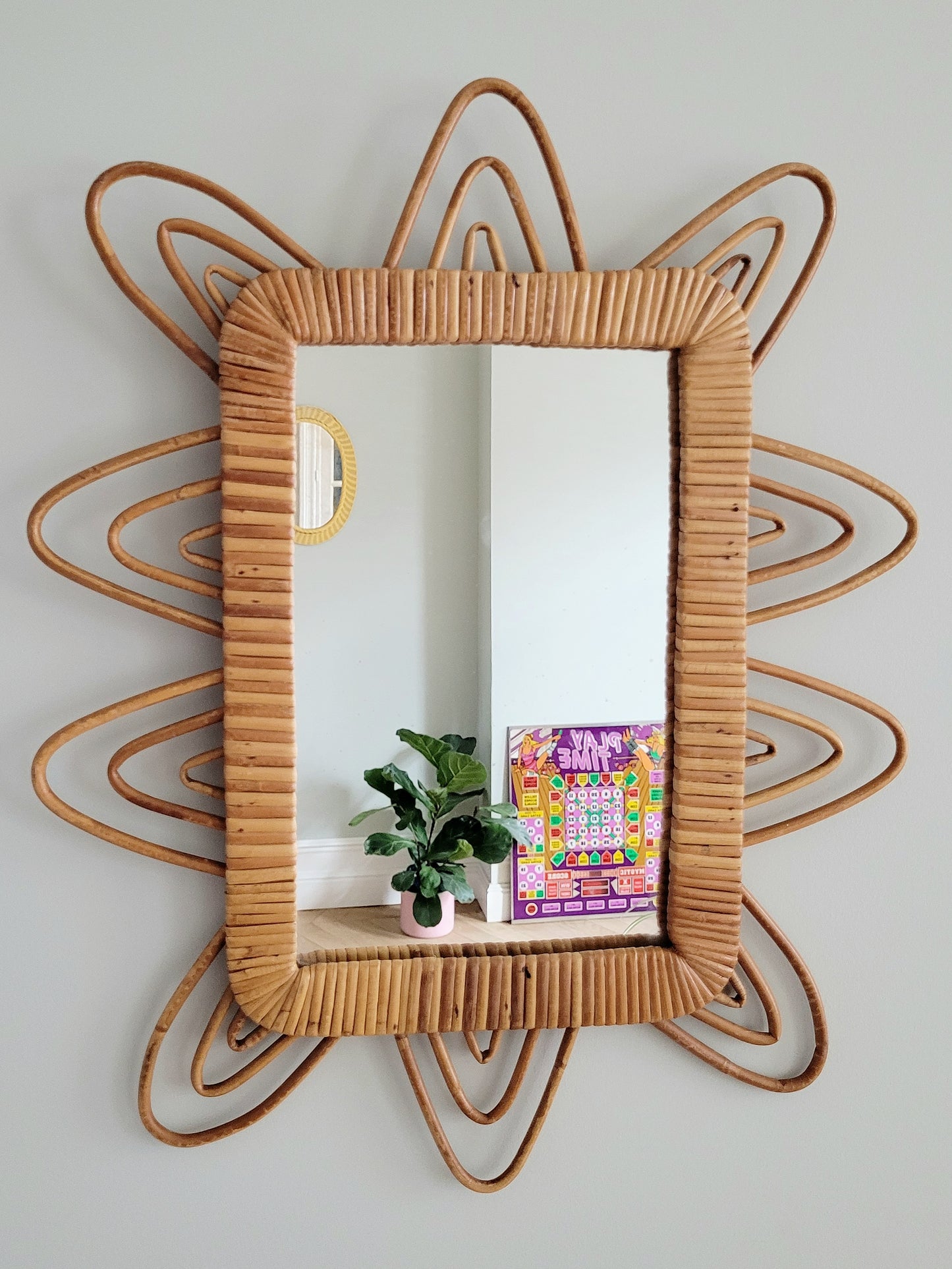 front view of a playful vintage wall mirror with rattan frame