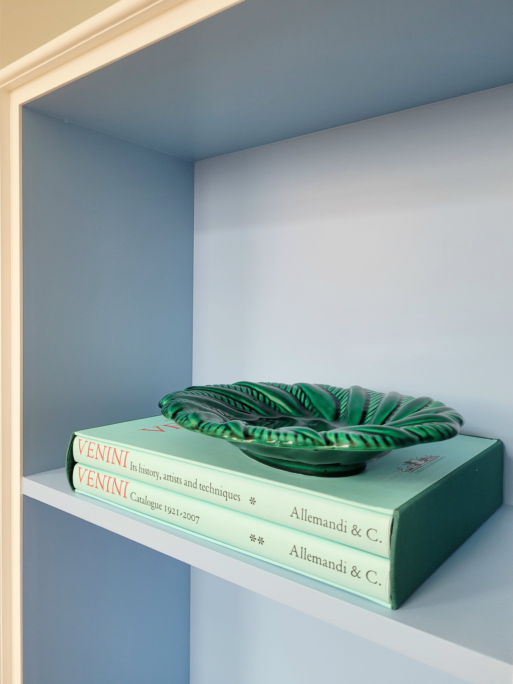 side view of a vintage green ceramic plate on a shelf