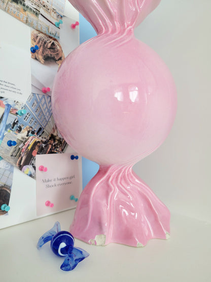 detail of a pink ceramic candy bonbon vase with a vision board next to it and a small Murano candy in the front