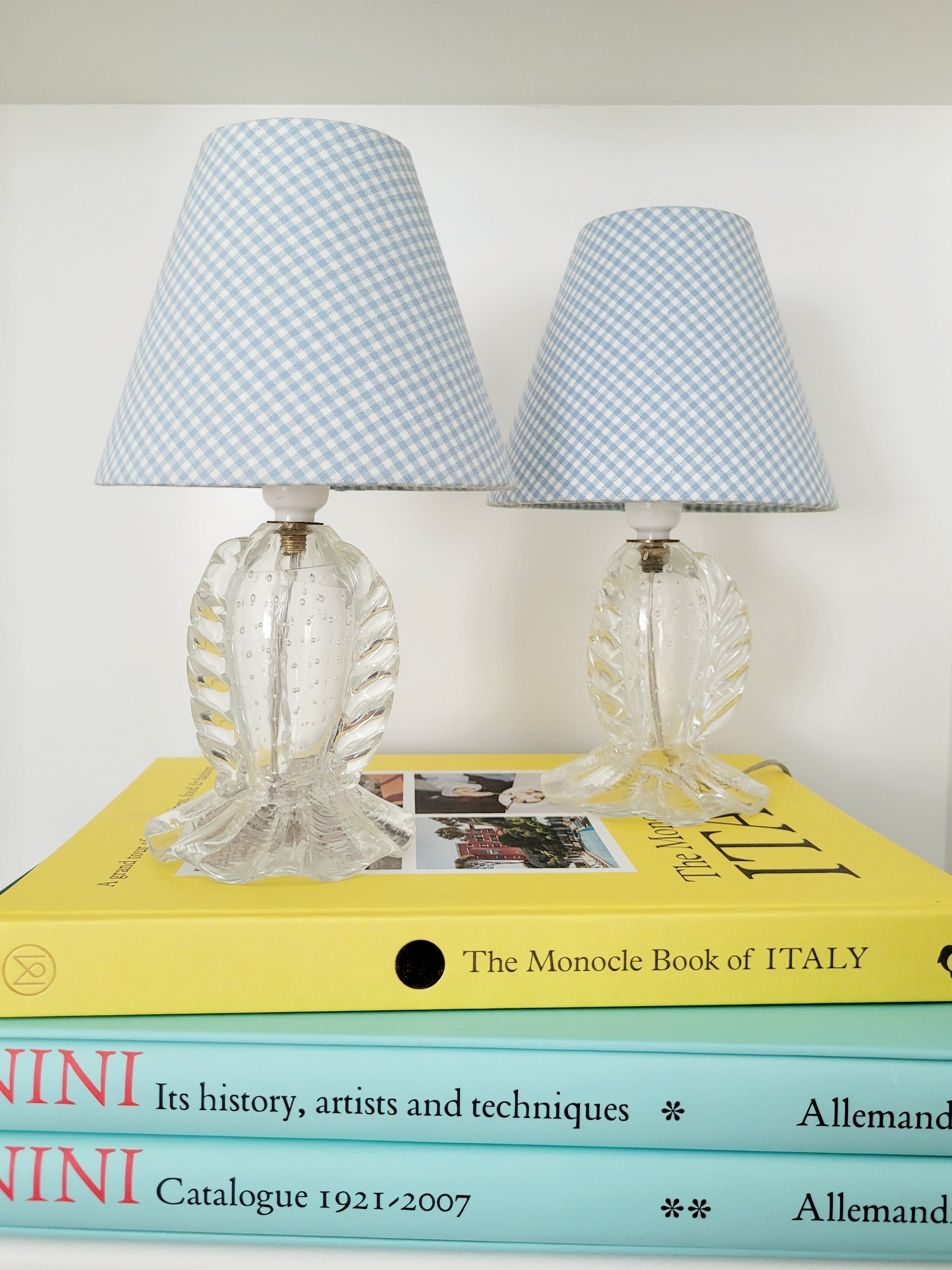 full view of a rare pair of vintage clear Murano table lamps with shades stacked on books 