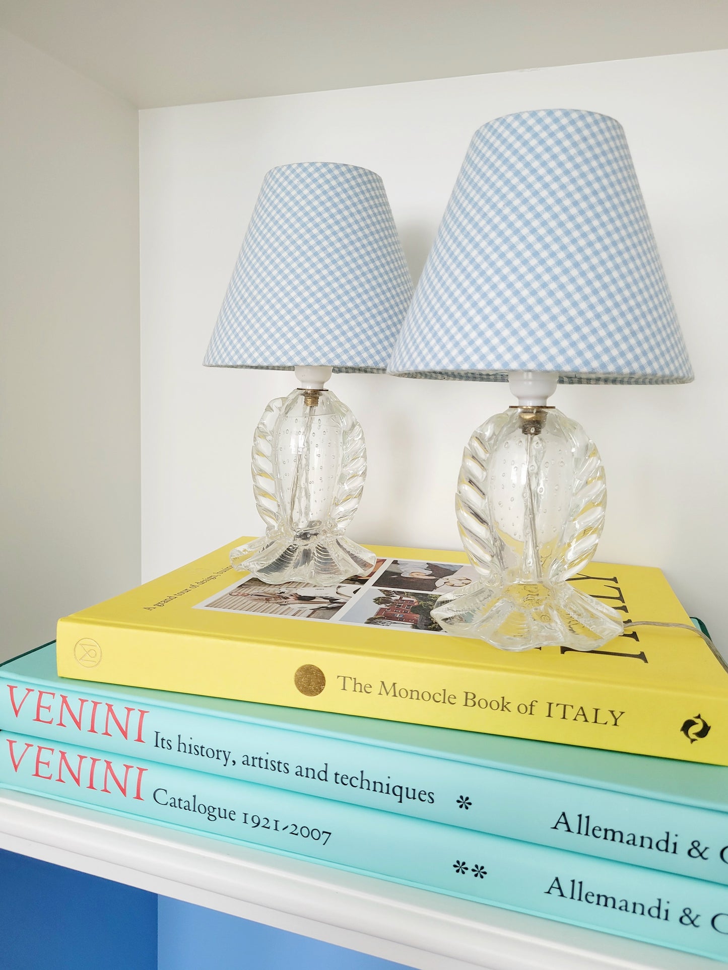 front view of a rare pair of vintage clear Murano table lamps with shades stacked on books