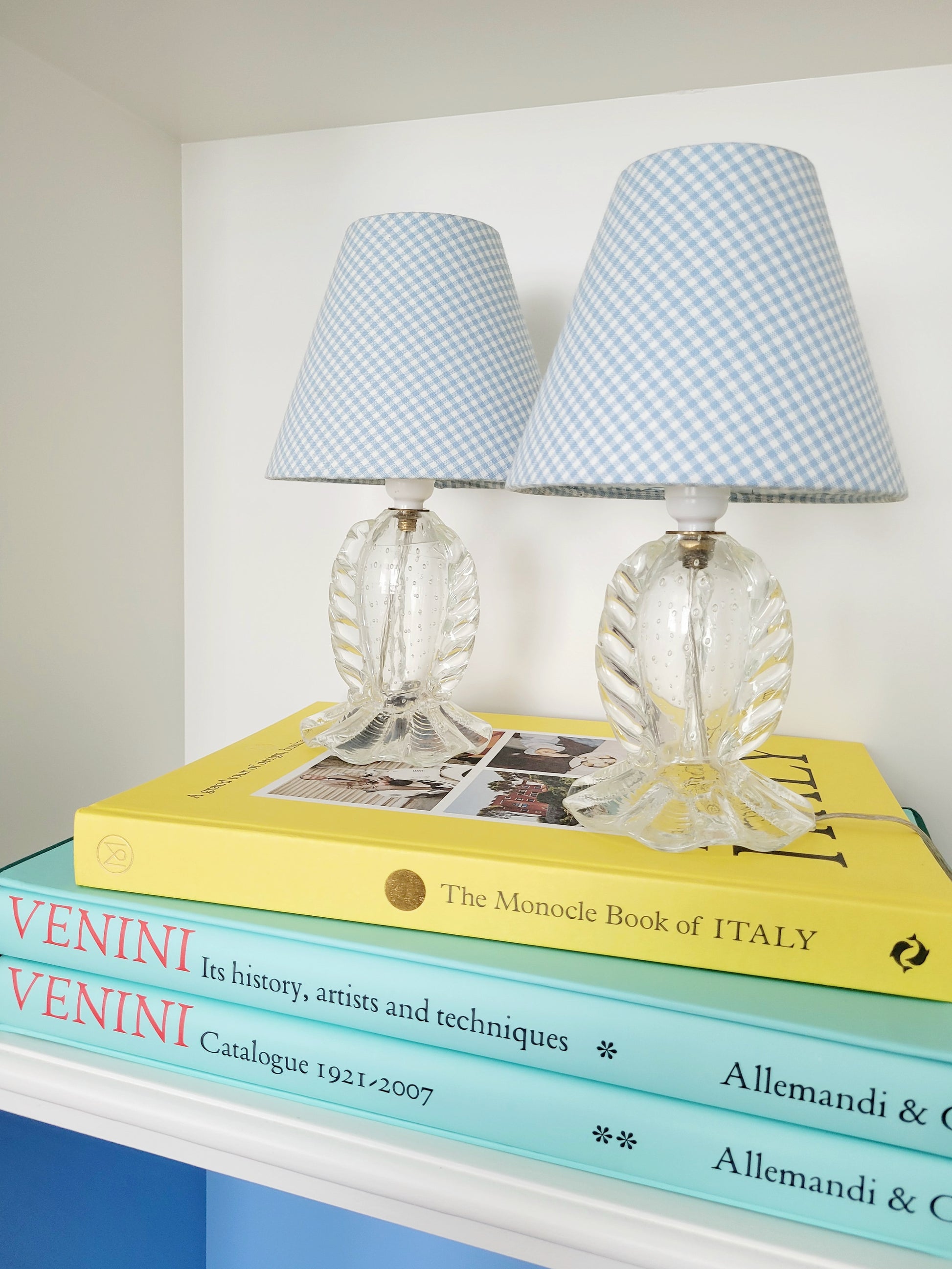 front view of a rare pair of vintage clear Murano table lamps with shades stacked on books