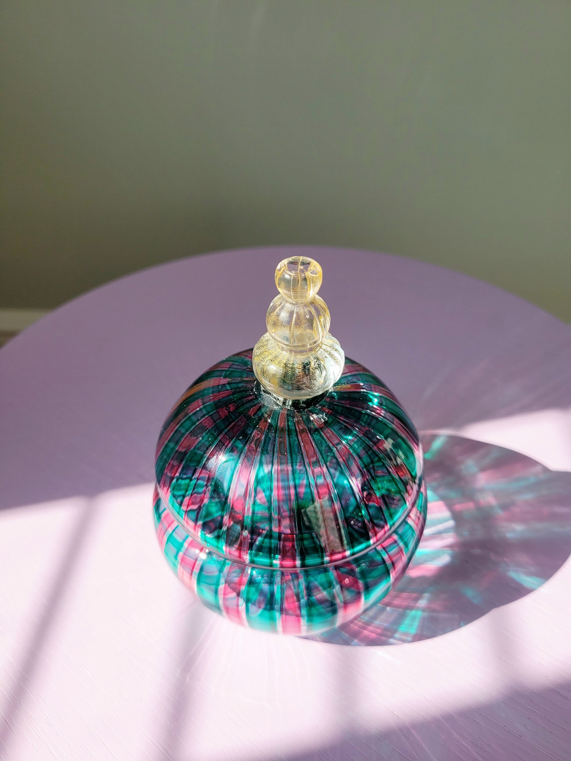 top view of a handcrafted vintage striped Murano bonbonniere in green pink and gold