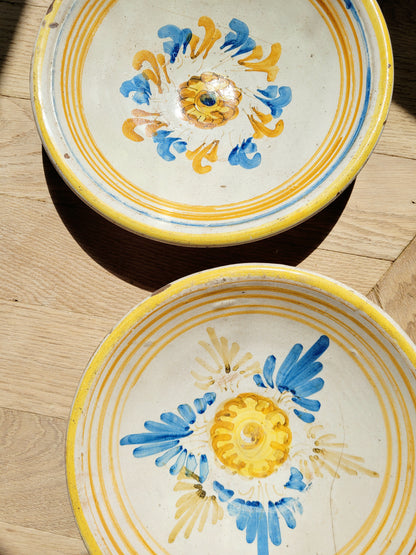 detail of a pair of antique ceramic (wall) plates, adorned in vibrant blue and yellow hues with a stunning flower pattern on a parquet floor