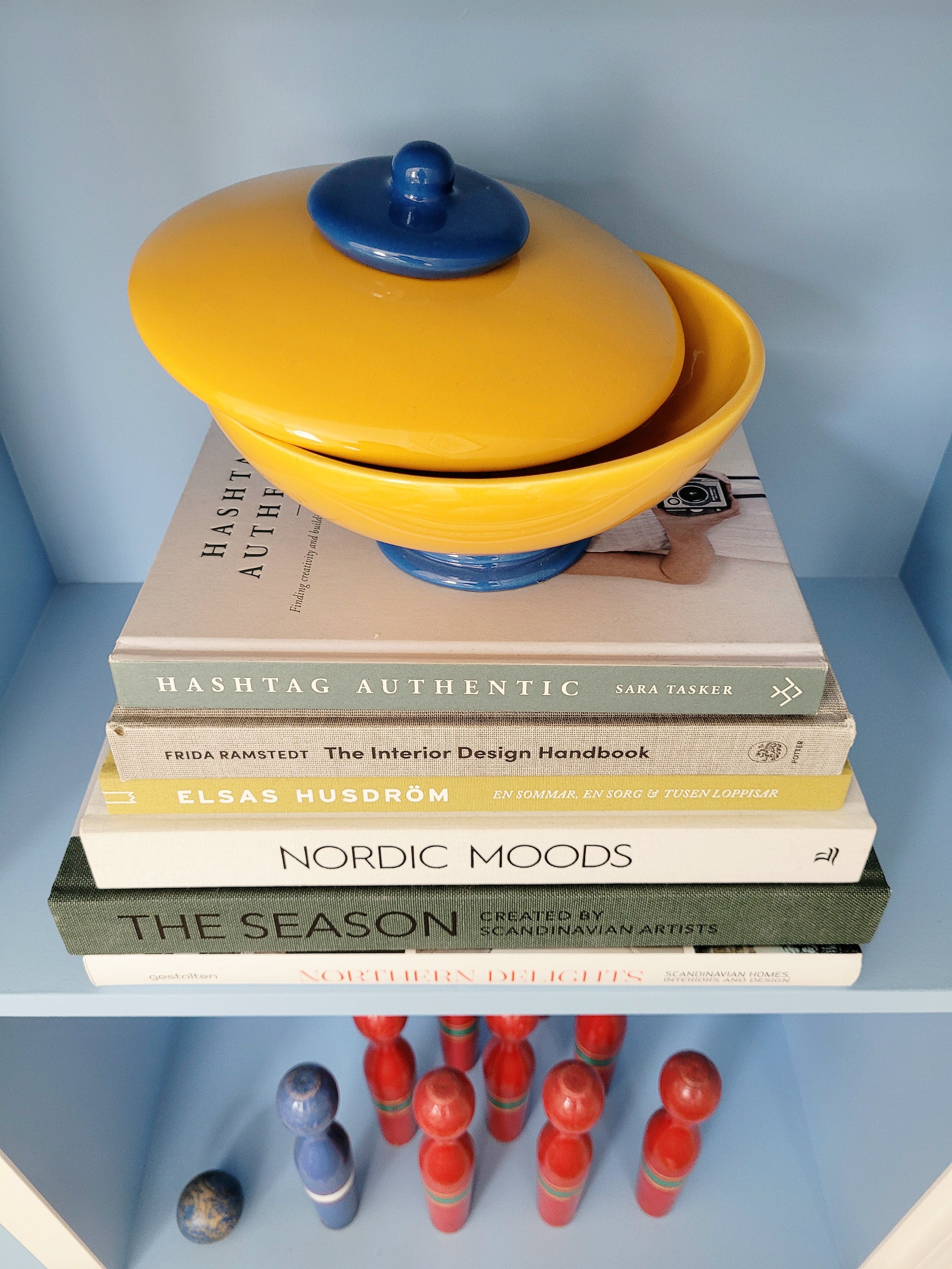 a ceramic jar in blue and yellow on a stack of interior books