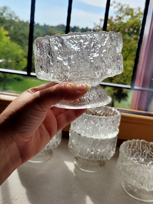 Crafted from heavy molded 'ice glass', these footed bowls feature a mesmerizing, bark-like texture that mimics natural Arctic ice. A complete set of six