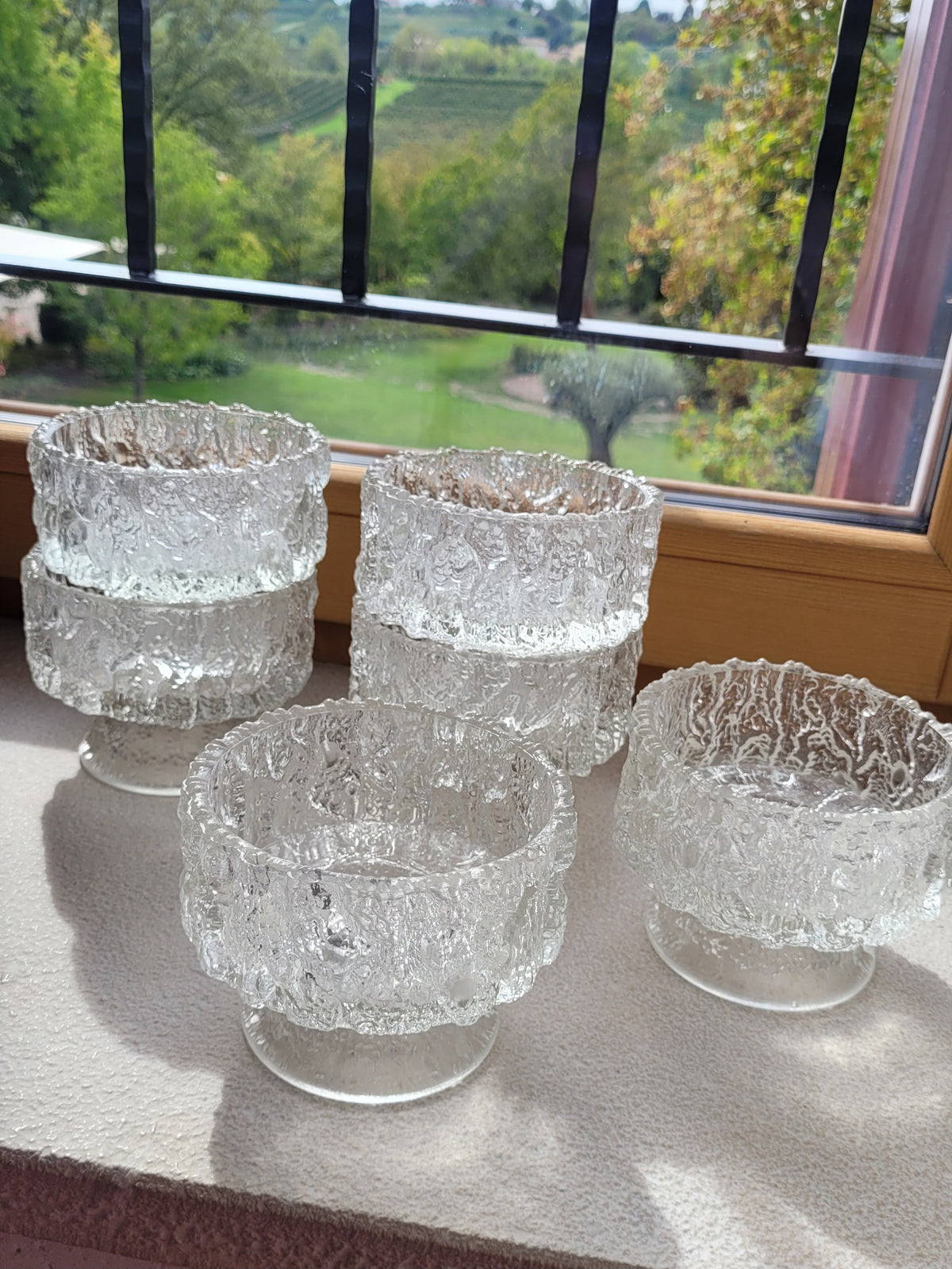 Crafted from heavy molded 'ice glass', these footed bowls feature a mesmerizing, bark-like texture that mimics natural Arctic ice. A complete set of six