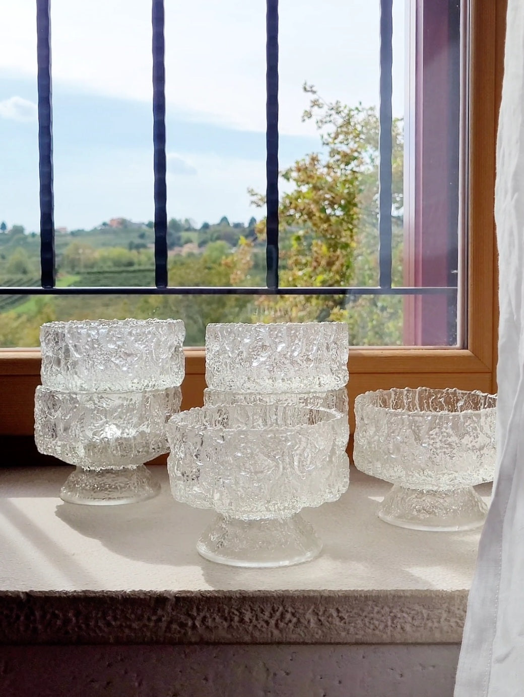 Crafted from heavy molded 'ice glass', these footed bowls feature a mesmerizing, bark-like texture that mimics natural Arctic ice. A complete set of six