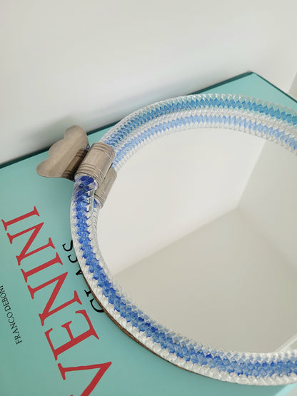 detail of an Italian mirror tray with twisted blue Murano glass frame on a stack of Venini books